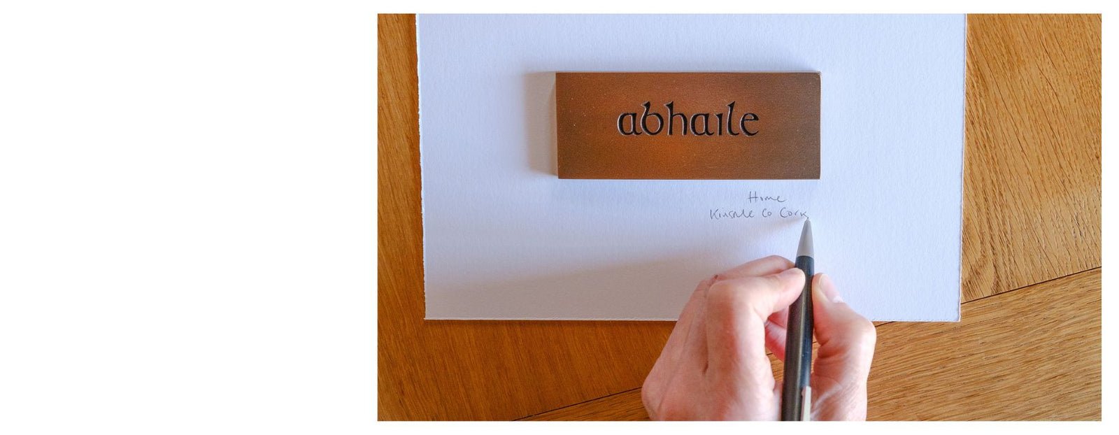 Hand writing on a piece of paper with a wooden desk and 'abhate' nameplate in the background